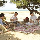 Personajes de 'El tiempo entre costuras' comen en la playa